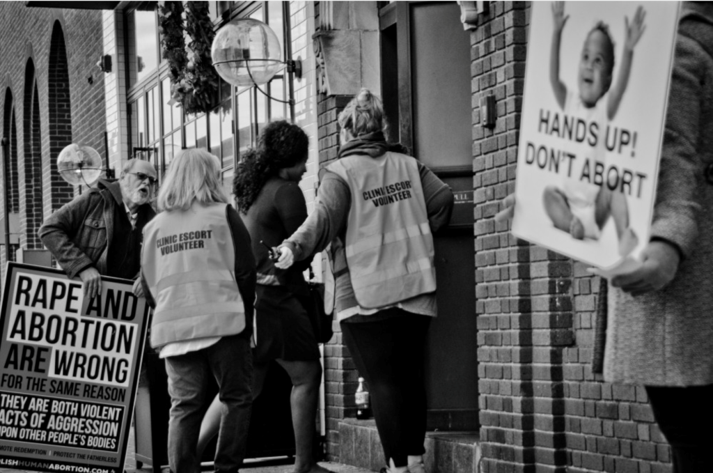 Protestors harass a patient outside of a women’s healthcare clinic. Photo by and courtesy of Wendi Kent. 